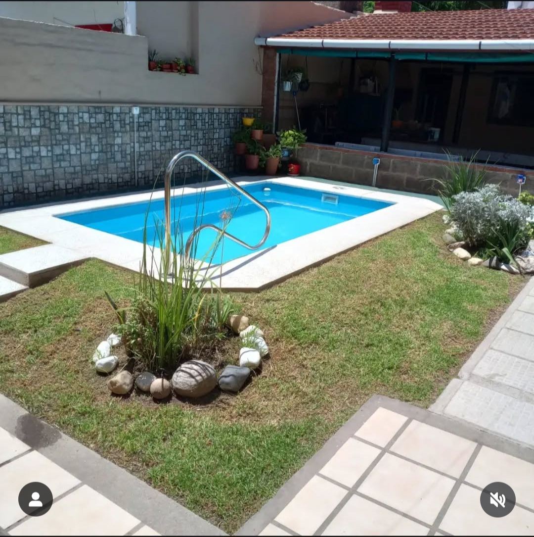 Pileta con escalera de acceso instalada en un patio con jardín